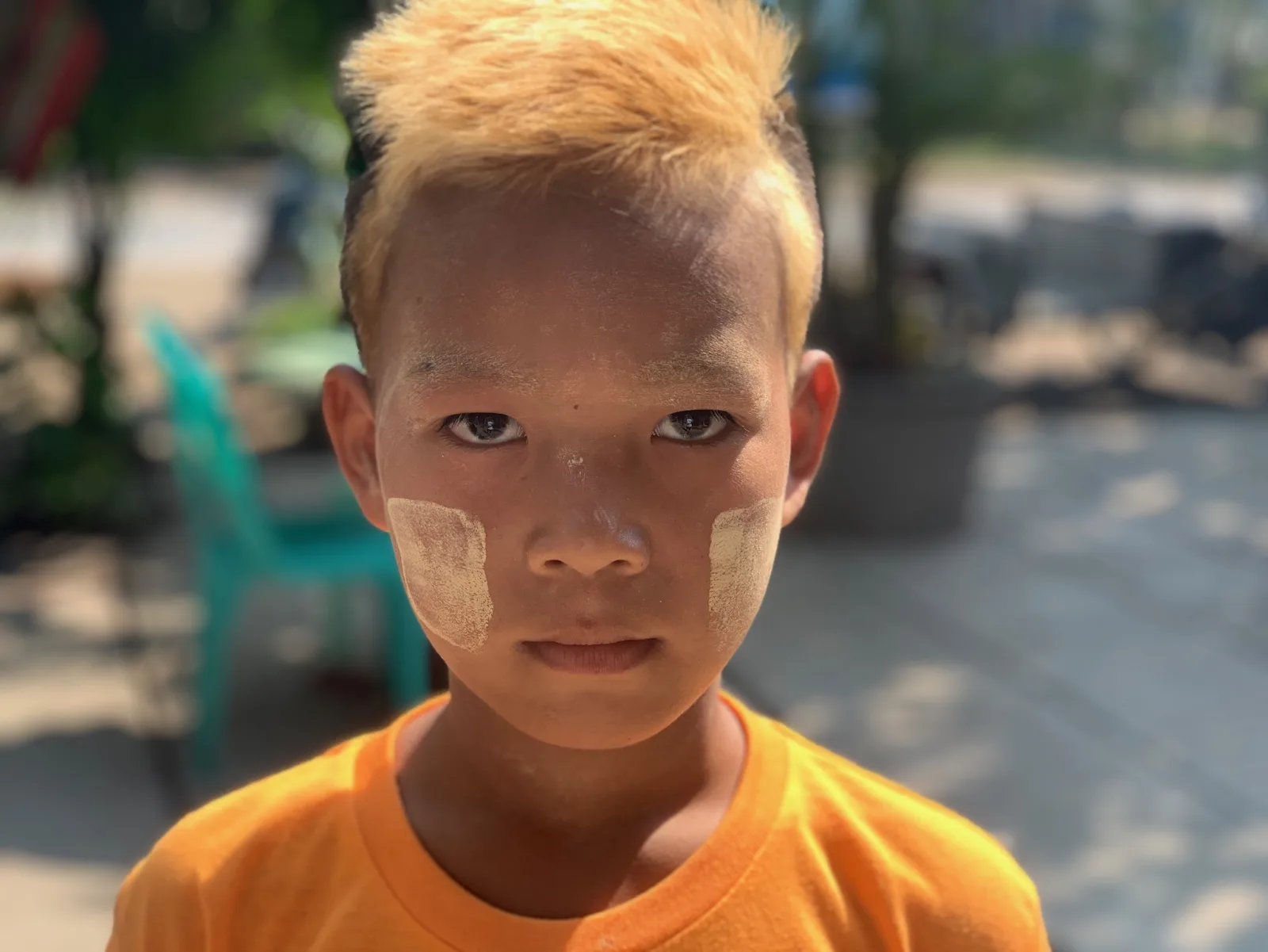 A young boy with thanaka on his cheeks looking straight at the camera